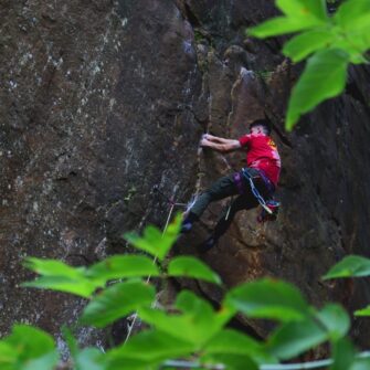 Climber on the face of a cliff making the move to the next hold